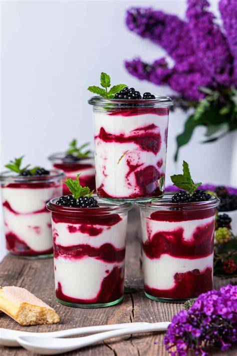 Verschiedene Schichten Pudding im Glas, dekoriert mit Beeren und Minze