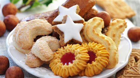 Verschiedene Weihnachtsplätzchen mit Haselnüssen auf rustikalem Brett