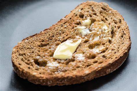 Waage mit Scheibe Vollkorntoast, Butterportion und Marmeladenglas