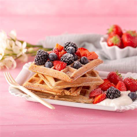 Waffeleisen mit frischen Dinkelwaffeln, Puderzucker und Beeren