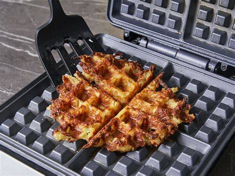 Waffeleisen mit goldbraunen Kichererbsen-Waffeln auf Teller