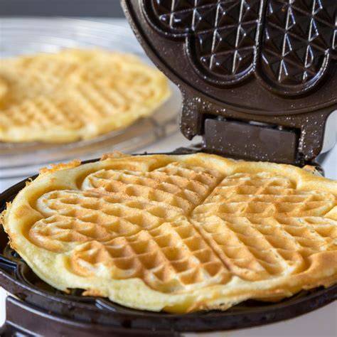 Waffeleisen und frische Waffeln auf Kuchengitter
