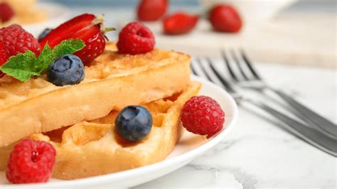 Waffeln mit frischen Früchten und Nutella auf Teller am Tisch