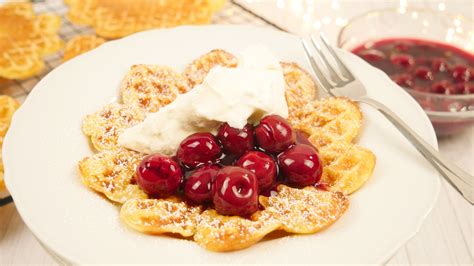 Waffeln mit heißen Kirschen und Sahne auf einem Teller