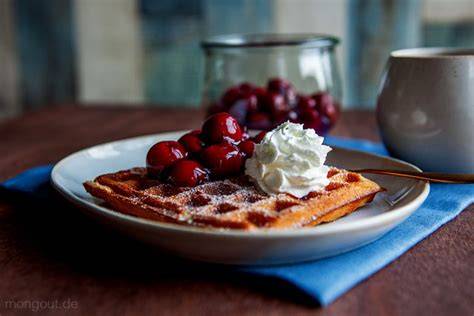 Waffeln mit heißen Kirschen und Vanilleeis auf einem Teller