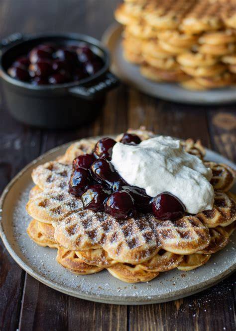 Waffelplatte mit heißen Kirschen, Sahne und Puderzucker