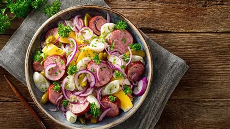 Wurstsalat mit Honig-Senf-Dressing auf einem Teller angerichtet