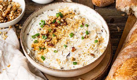 Ziegenfrischkäse und Honig Dip auf Holzbrett mit Kräutern