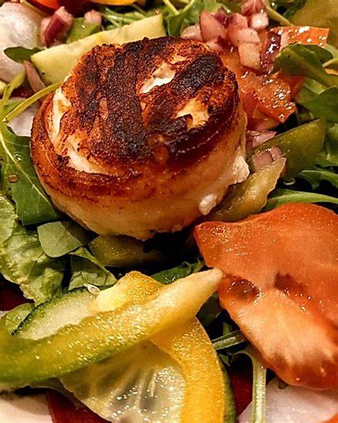 Ziegenkäsetaler auf Blattsalat mit Honig und Nüssen angerichtet, nah aufgenommen