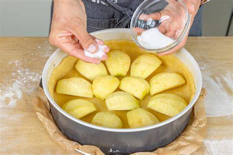 Zimt-Zucker über Apfelkuchen streuen