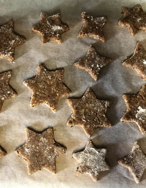 Zimtsterne auf Backpapier, daneben Schälchen mit Eierlikörglasur und Pinsel zum Bestreichen