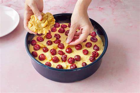 Zubereitung Streuselkuchen: Teig in Springform drücken, Kirschen verteilen, Streusel darüber geben