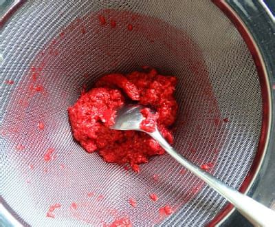 Zubereitungsschritte: Pürierte Himbeeren werden durch ein Sieb gestrichen