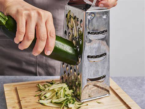 Zucchini raspeln und Zutaten auf einer Arbeitsfläche