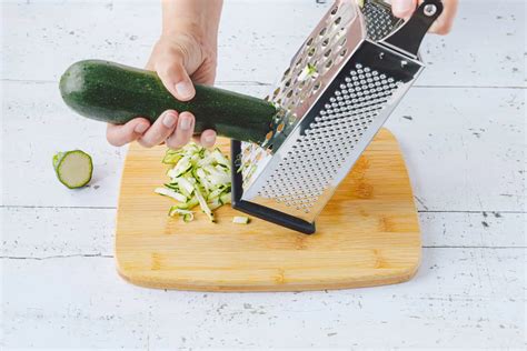 Zucchini und geraspelte Zucchini auf einer Reibe