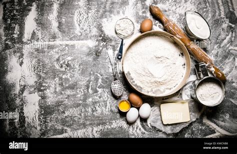 Zutaten auf einem Holzbrett: Mehl, saure Sahne, Eier, Butter und Puderzucker