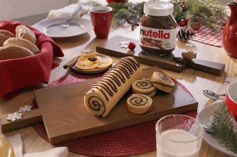 Zutaten für eine klassische Biskuitrolle mit Nutella auf einem Holztisch arrangiert