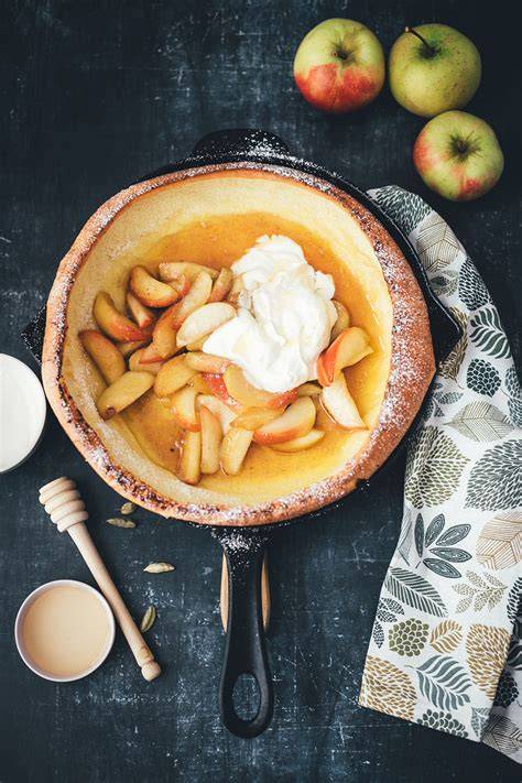 Zutatenstillleben: Mehl, Öl, Wasser, Crème fraîche, Zucker, Zimt und Äpfel auf Arbeitsfläche