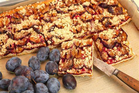 Zwetschgen Käsekuchen vom Blech mit Streuseln, angerichtet auf einem Holzbrett
