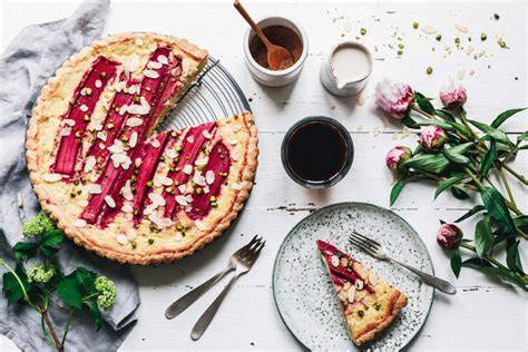 anschnitt veganer rhabarber-käsekuchen mit himbeer-sahne-topping