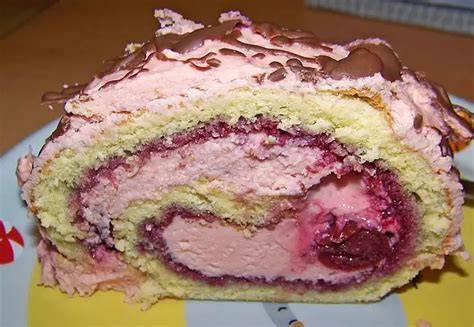 aufgerollte Biskuitrolle mit Buttercreme auf Schneidebrett