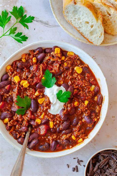 dunkles Chili con Carne in Schüssel mit Maisbrot