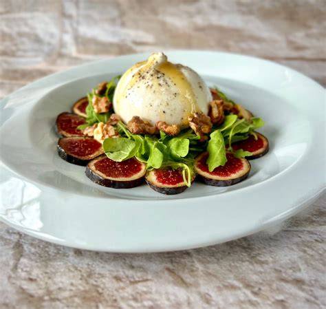 eine saftige Burrata mit frischen Trüffelscheiben auf Rucola serviert