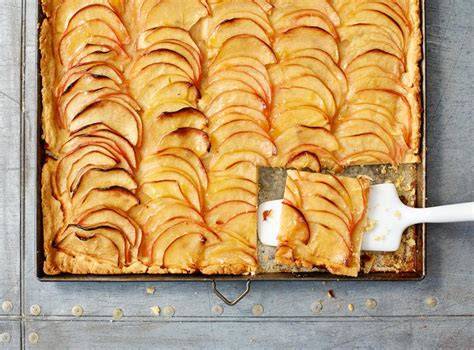 frisch gebackener französischer Apfelkuchen auf dem Blech, mit dünnen Apfelscheiben und Puderzucker