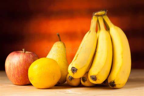 frische Äpfel, Birnen und Bananen auf einem Holztisch, daneben Marmeladengläser