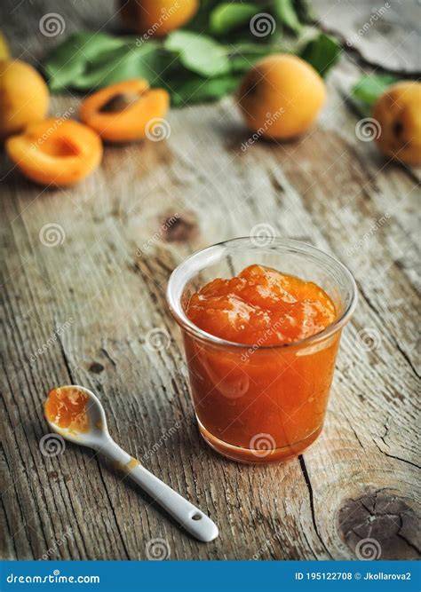 frische Aprikosen und Marmeladengläser auf Holztisch