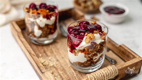 frisches Granola mit Nüssen im Glas angerichtet, dazu frisches Obst