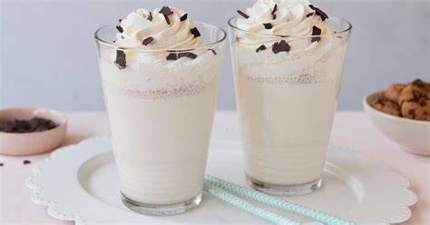 gläser mit vanille-milchshake, sahnetuffs und schokostreuseln