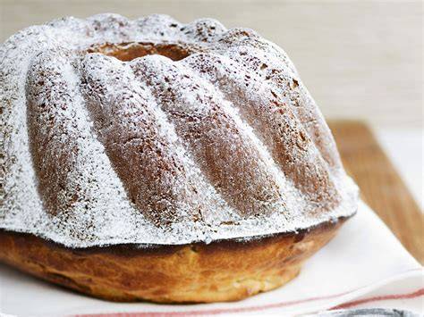 klassischer Gugelhupf Kuchen auf Holzbrett mit Puderzucker