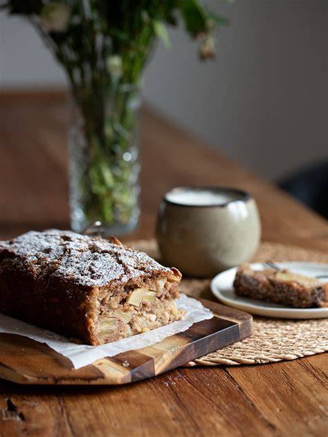 kleiner apfel-mandel-kuchen goldbraun auf holzbrett, herbstliche deko