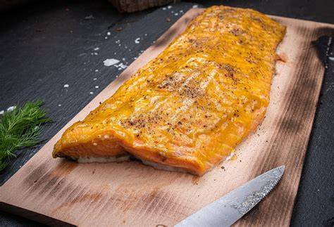 lachs auf holzplanke mit honig-senf-kruste grillt über offenem feuer