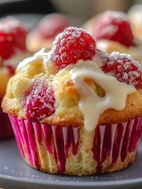 nahaufnahme: aufgebrochener muffin mit sichtbar geschmolzenen weißen schokostücken und himbeeren