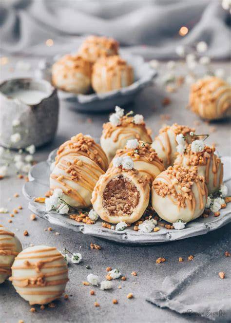 nahaufnahme: pralinen in gehackten haselnüssen und mandeln, einzelne mit silberperle