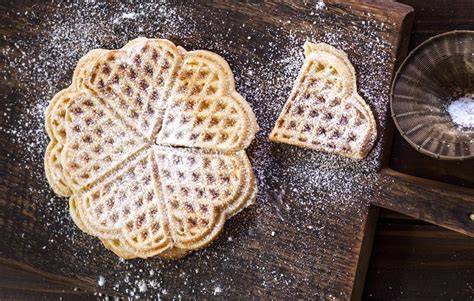 nahaufnahme von zarten waffelkeksen, frisch gebacken auf einem gitter, mit puderzucker bestäubt