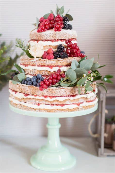 naked cake mit blumenkranz und früchten