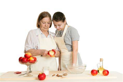 oma und enkelin schneiden gemeinsam einen kuchen mit biskuitboden an