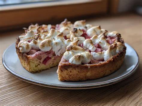 rhabarber-baiser-kuchen mit goldbrauner haube auf kuchenplatte