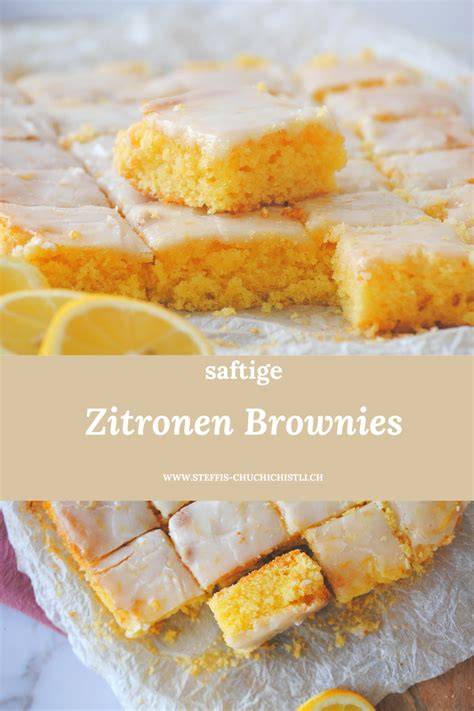 servierte Zitronen-Brownies mit weißem Guss auf Holzbrett, Zitronenscheiben und weißer Schokolade