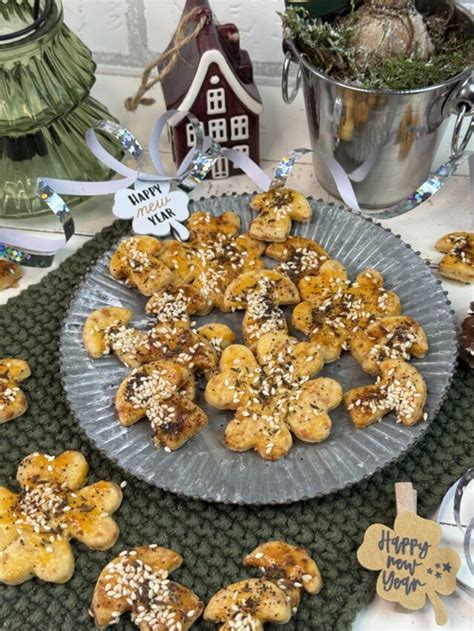 serviervorschlag: käsekekse auf holzbrett mit sesam, mohn und kümmel, glas wein daneben