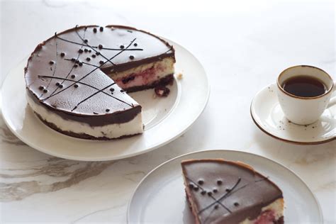 serviervorschlag: stück schoko-kirsch-torte auf teller, kaffee daneben