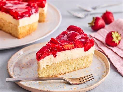 serviervorschlag: stueck erdbeer-schmand-kuchen auf teller mit kaffeetasse