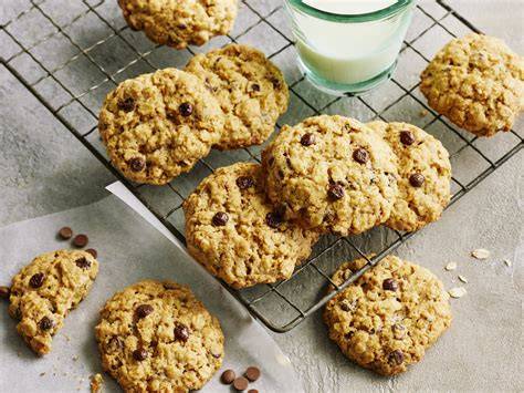 stimmungsvolle ansicht von cookies mit schoko-drops auf backpapier, zutaten und rührschüssel