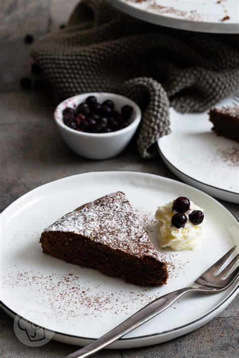 typischer schwedischer Kladdkaka auf Teller, mit Puderzucker und Beeren