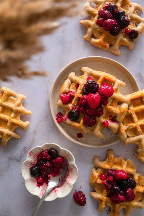 verschiedene Toppings für glutenfreie Waffeln: Beeren, Sirup, Puderzucker