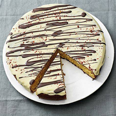 weißer schokoladenkuchen angerichtet auf kuchenplatte mit dekor
